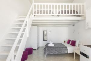 a white bedroom with a bed and a staircase at Irene's Residence in Mikonos