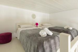 Dos camas en una habitación con paredes blancas. en Irene's Residence, en Mykonos ciudad