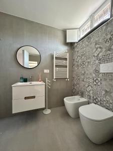 une salle de bain avec un lavabo, des toilettes et un miroir dans l'établissement Sunshine Apartment Acireale, à Acireale