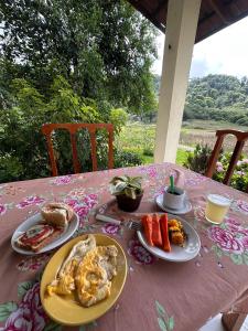 une table rose avec des assiettes de nourriture dessus dans l'établissement Chalé Suíço - Chalés Belo Monte - Sítio Belo Monte, à Pacoti