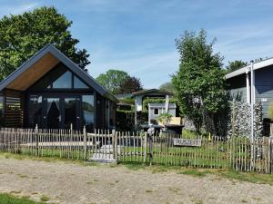 a black house with a fence in front of it at Tiny Haus Auszeit am See in Lathum