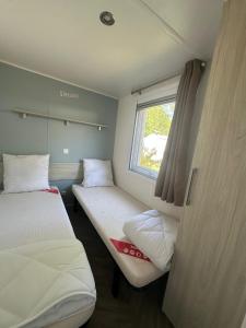 two beds in a small room with a window at La Palmyre - Les Mathes - Nouveau Mobil home - Camping 4 étoiles "Les Charmettes" in Les Mathes