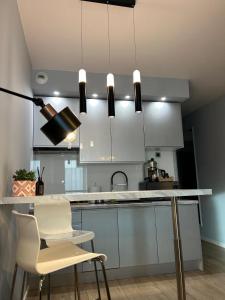 a kitchen with white cabinets and a counter with chairs at Rajska 3 in Kraków +4 photos