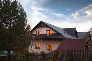 una casa bianca con un tetto nero e una recinzione di Ubytovanie Eva a Oščadnica