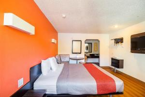 a hotel room with a bed with an orange wall at Economy Hotel Kansas City in Blue Springs