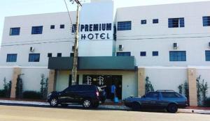 two cars parked in front of a hotel at Premium Hotel Frutal in Frutal