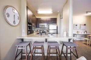 a kitchen with three bar stools and a clock on the wall at Spacious 2BDR Condo near Venice Beach in Los Angeles