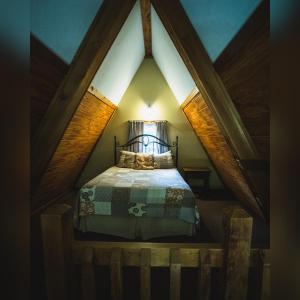 a small bedroom with a bed in a attic at A-Frame #01 - by The Chalets in Logan +15 photos