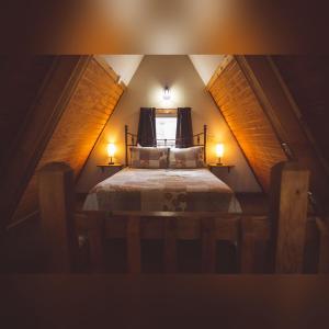 a small attic bedroom with a bed with two lamps at A-Frame #02 - by The Chalets in Logan +12 photos