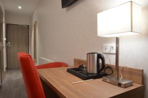 a coffee maker on a wooden table with red chairs at Logis Hôtel - La Chambre d'Amiens in Amiens