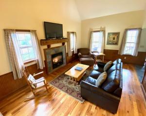 a living room with a leather couch and a fireplace at Deer Run - by The Chalets in Logan
