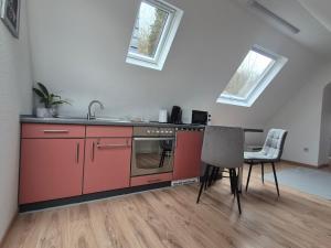 a kitchen with red cabinets and a table and chairs at Schumacher Ferienwohnung in Netphen