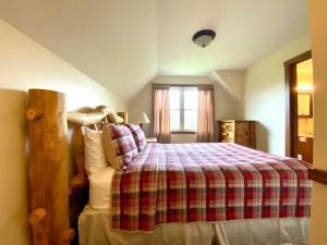 a bedroom with a bed with a plaid blanket and a window at Deer Run - by The Chalets in Logan