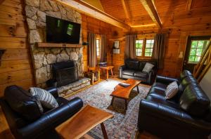 a living room with leather furniture and a stone fireplace at Dogwood - by The Chalets in Logan