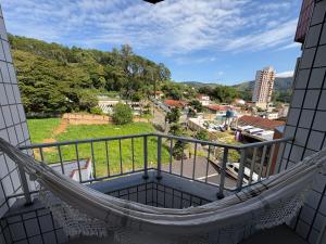 a hammock on a balcony overlooking a city at Apartamento no centro de São Lourenço e a 750 metros do parque in São Lourenço