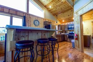 a kitchen with three bar stools at a counter at Overlook - by The Chalets in Logan