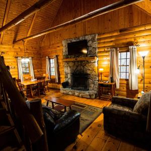 a living room with a stone fireplace in a log cabin at Pioneer - by The Chalets in South Bloomingville