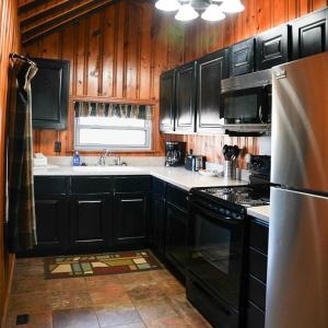 a kitchen with black cabinets and a stainless steel refrigerator at Settler - by The Chalets in Logan +12 photos