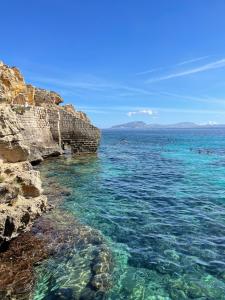 a group of people swimming in the ocean near rocks at Favignana in centro con terrazza in Favignana