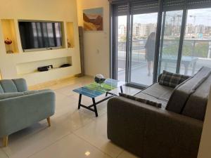 a living room with two couches and a glass table at רויאל פארק פרימיום in Eilat