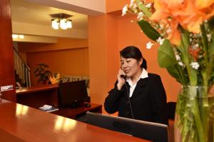 a woman sitting at a desk talking on a cell phone at Casa Real Hoteles in Cusco