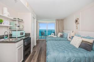 マートルビーチにあるNew Luxury Oceanfront 2BR Condo with Relaxing Ambianceのベッド1台付きの部屋、バルコニー付きのキッチンが備わるアパートメントです。