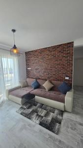 a living room with a couch against a brick wall at Happy Architect in Cisnădie
