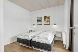 a bed in a white room with two pictures on the wall at Beautiful harbor view apartment in Hvide Sande