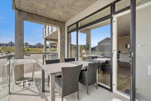 a dining room with glass doors and a table and chairs at Beautiful harbor view apartment in Hvide Sande