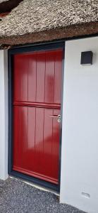 a red garage door on the side of a building at Bed and Breakfast 't Klokhuis in Langedijke