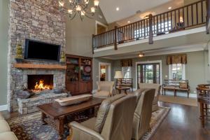 a living room with a stone fireplace and a tv at Grand Family Retreat 8Br With Stunning Golf Views in Mill Spring
