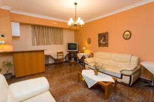 a living room with white furniture and a tv at Orion Studios in Loutra Edipsou
