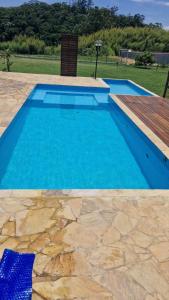 a swimming pool with blue water in a yard at Recanto Girassol em São Roque - Rota do Vinho in São Roque +21 photos