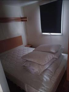 a bed with pillows and a window in a bedroom at Mobil home avec terrasse couverte Les Phoques in Berck-sur-Mer