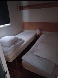 two twin beds in a room with a window at Mobil home avec terrasse couverte Les Phoques in Berck-sur-Mer +1 photo