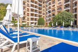 a hotel swimming pool with chairs and umbrellas at Hermann's Sea View Apartment - Bendita Mare in Varna City