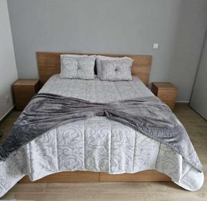 a bed with a gray and white comforter and pillows at Alojamentos pinheiros in Amarante