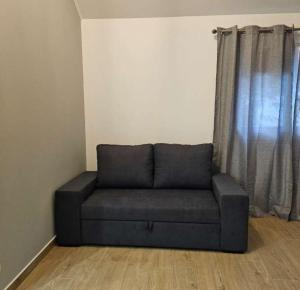 a couch sitting in a living room with a window at Alojamentos pinheiros in Amarante