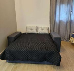 a black bed in a room with a window at Alojamentos pinheiros in Amarante