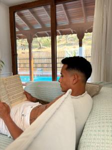 un homme allongé dans un hamac en train de lire un livre dans l'établissement Milas-Bodrum Özel Havuzlu Triplex Villa, à Milas