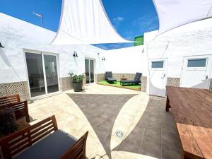 Un patio con bancos y mesas y un edificio blanco. en Casa Caladero, en El Golfo