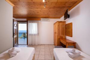 two beds in a room with a view of the ocean at Archodissa Pansion in Alyki