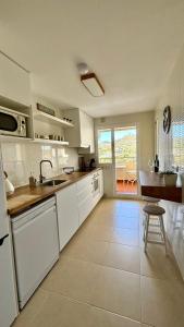 a kitchen with white cabinets and a sink and a table at Luna home in Torrox