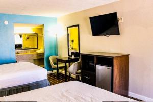 a hotel room with two beds and a desk with a television at Days Inn by Wyndham Little River in Little River