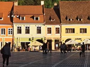 a group of people walking down a street with buildings at 4 Rooms Piata Sfatului in Braşov