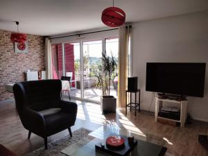 a living room with a flat screen tv and a chair at Lawrence House Barnes in Bidart