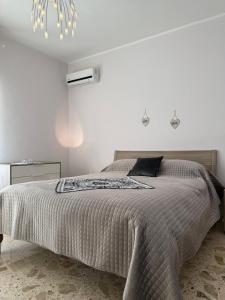 a white bedroom with a bed and a chandelier at Villa Annunziata Suite in Aragona