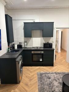 a kitchen with black cabinets and a stove top oven at Stylish flat near city centre in Cardiff