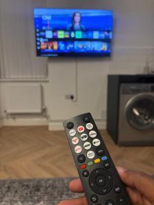 a person holding a remote control in front of a television at Stylish flat near city centre in Cardiff