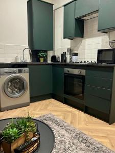 a kitchen with green cabinets and a table with plants at Stylish flat near city centre in Cardiff +8 photos